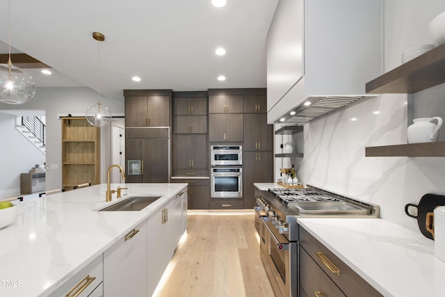 5812 Shawood Dr, Raleigh, NC 27609 - kitchen with range with two ovens, a sink, light wood-style flooring, light stone countertops, and pendant lighting