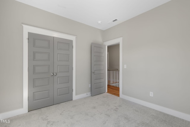 unfurnished bedroom featuring a closet and light colored carpet