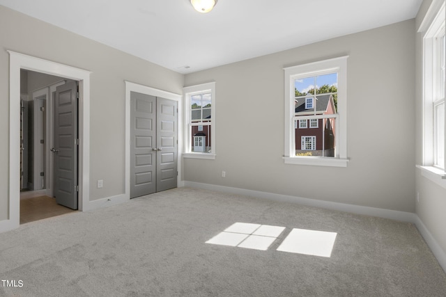 unfurnished bedroom with light carpet and a closet