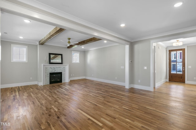 unfurnished living room with a tile fireplace, hardwood / wood-style floors, beamed ceiling, and a healthy amount of sunlight