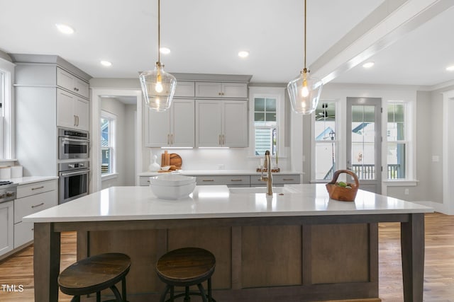 kitchen featuring gray cabinets, a breakfast bar, a spacious island, and decorative light fixtures