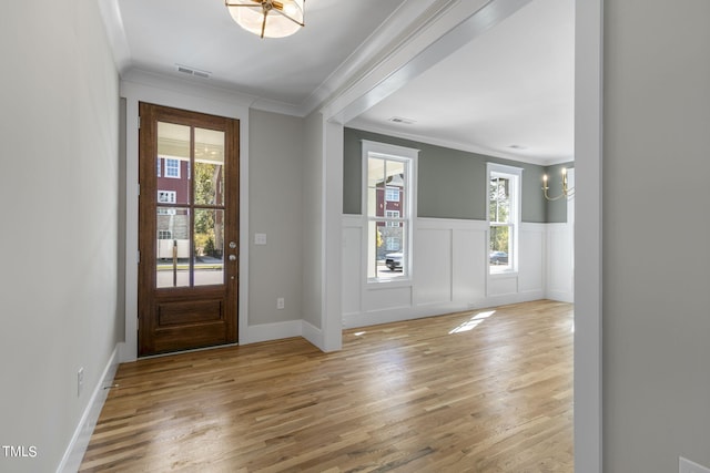 entrance foyer featuring a notable chandelier, crown molding, and light hardwood / wood-style floors