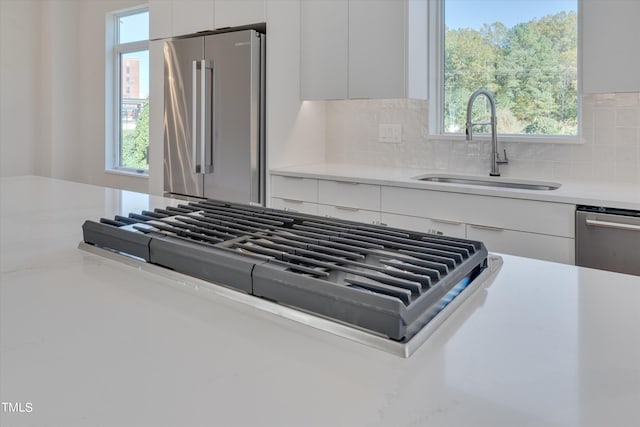 kitchen featuring appliances with stainless steel finishes, plenty of natural light, sink, and white cabinets