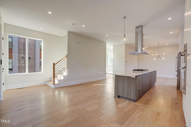 kitchen with decorative light fixtures, plenty of natural light, a kitchen island, island exhaust hood, and light hardwood / wood-style floors