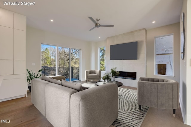 living room featuring hardwood / wood-style floors, a large fireplace, and ceiling fan