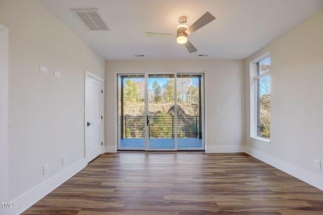 empty room with plenty of natural light, ceiling fan, and dark hardwood / wood-style floors