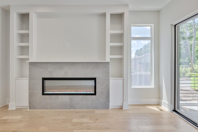 room details featuring built in features, a tiled fireplace, and hardwood / wood-style flooring