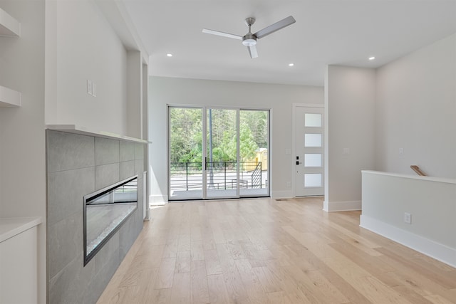 unfurnished living room featuring a fireplace, ceiling fan, and light wood-type flooring