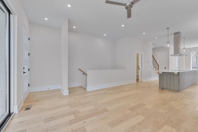 unfurnished living room with ceiling fan, plenty of natural light, and light hardwood / wood-style flooring