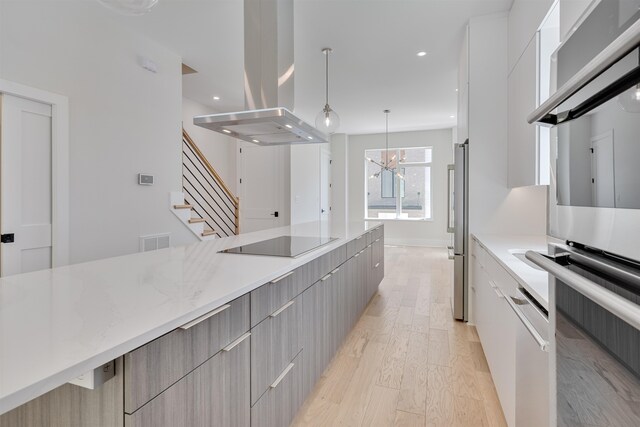 kitchen featuring a notable chandelier, light hardwood / wood-style floors, island exhaust hood, hanging light fixtures, and black electric stovetop