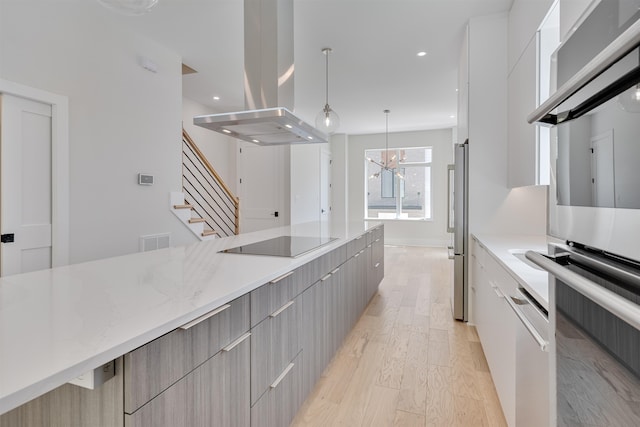 kitchen with an inviting chandelier, light hardwood / wood-style flooring, pendant lighting, island exhaust hood, and stainless steel appliances