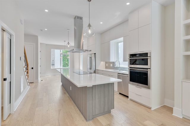 kitchen with a spacious island, hanging light fixtures, island exhaust hood, stainless steel appliances, and white cabinets