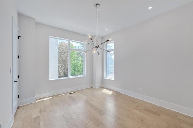 unfurnished room with light hardwood / wood-style flooring and an inviting chandelier