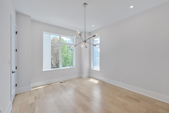 spare room with a chandelier and light hardwood / wood-style floors