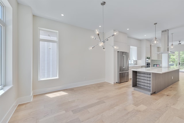 kitchen featuring sink, white cabinetry, hanging light fixtures, a kitchen island, and stainless steel appliances