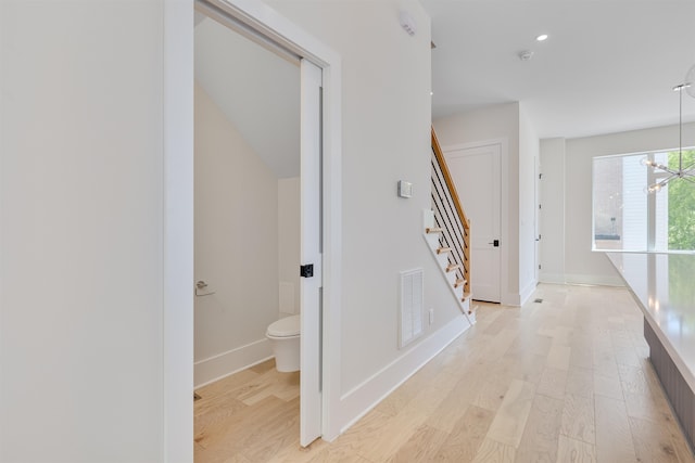 corridor featuring light hardwood / wood-style flooring and a chandelier