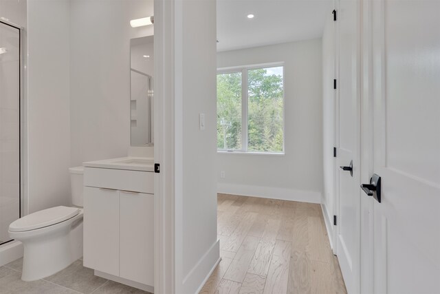 bathroom with walk in shower, vanity, toilet, and hardwood / wood-style flooring