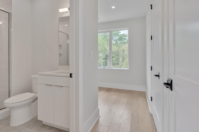 bathroom with hardwood / wood-style flooring, vanity, a shower with shower door, and toilet