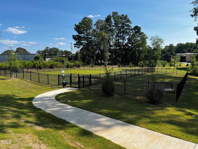 view of property's community featuring a lawn and fence