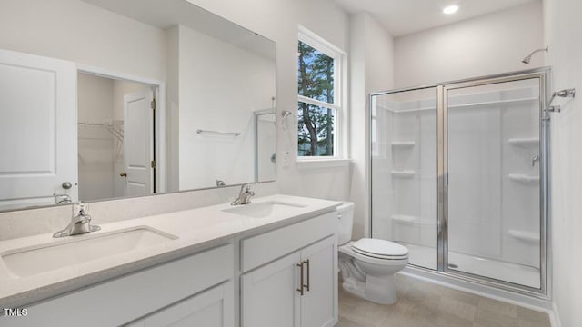 bathroom with a stall shower, a sink, toilet, and double vanity