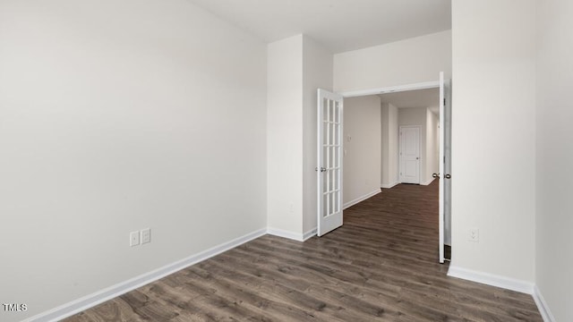 spare room featuring dark wood-type flooring and baseboards