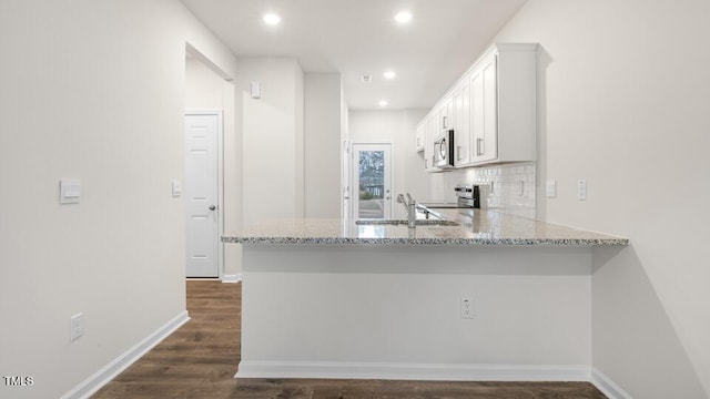 kitchen with appliances with stainless steel finishes, decorative backsplash, white cabinetry, and light stone countertops