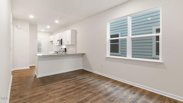 kitchen with dark wood-style floors, stainless steel microwave, range, and white cabinetry