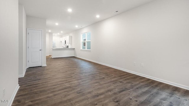 spare room with baseboards, dark wood-style flooring, and recessed lighting