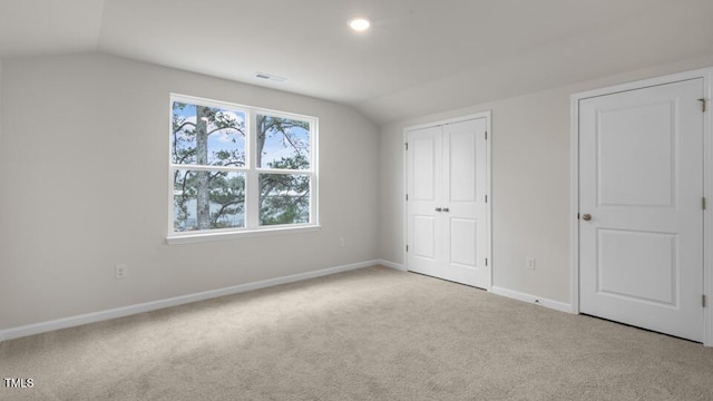 unfurnished bedroom with vaulted ceiling, carpet flooring, visible vents, and baseboards