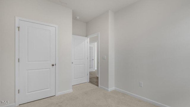 unfurnished bedroom with baseboards and light colored carpet