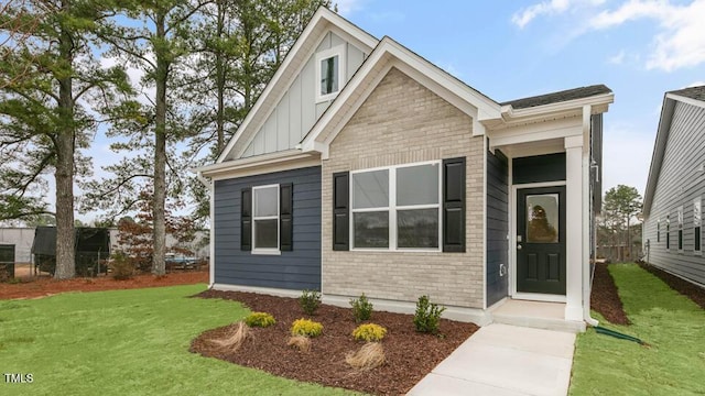 view of front of property featuring board and batten siding, brick siding, and a front lawn