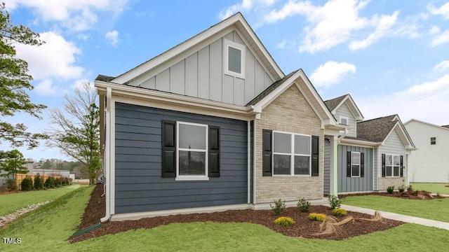 view of front of home featuring board and batten siding, a front yard, and brick siding