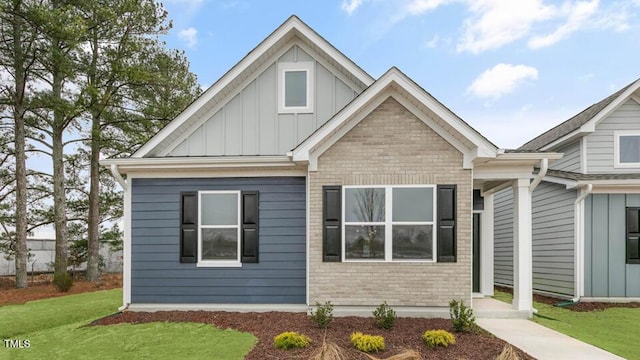 view of front of home featuring brick siding, board and batten siding, and a front lawn