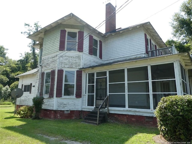 back of property featuring a sunroom and a lawn