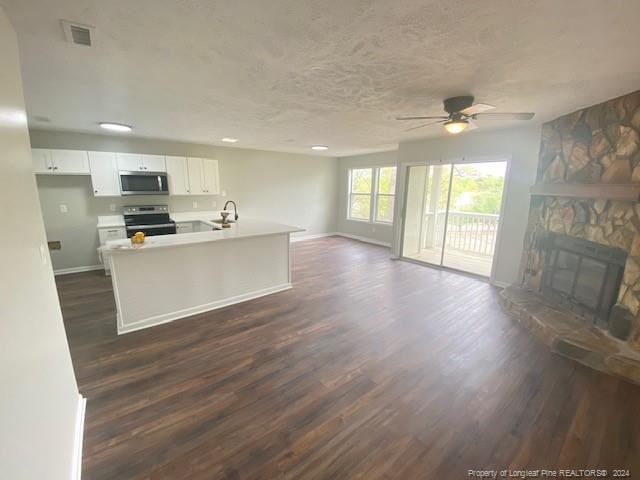 kitchen with a fireplace, ceiling fan, dark hardwood / wood-style flooring, white cabinets, and appliances with stainless steel finishes