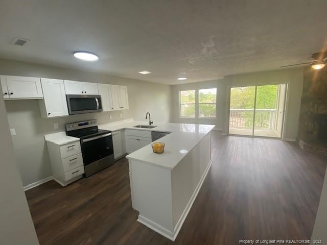 kitchen with sink, white cabinetry, stainless steel appliances, dark hardwood / wood-style flooring, and kitchen peninsula