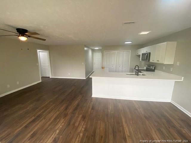 kitchen with sink, dark wood-type flooring, white cabinetry, stainless steel appliances, and kitchen peninsula