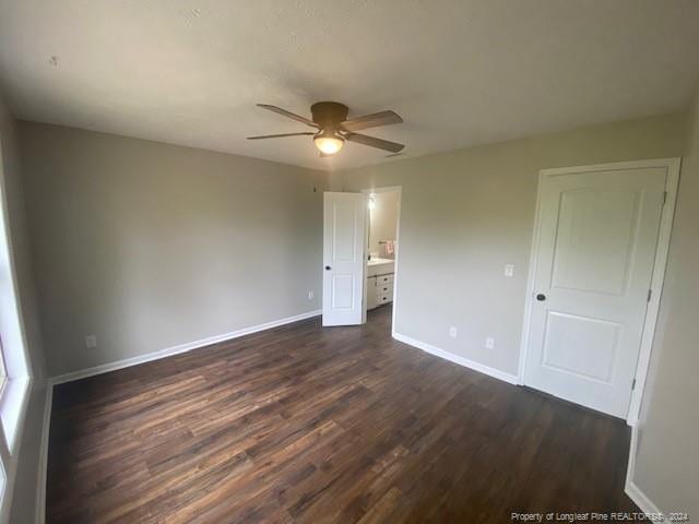 unfurnished bedroom featuring ceiling fan, ensuite bathroom, and dark hardwood / wood-style floors