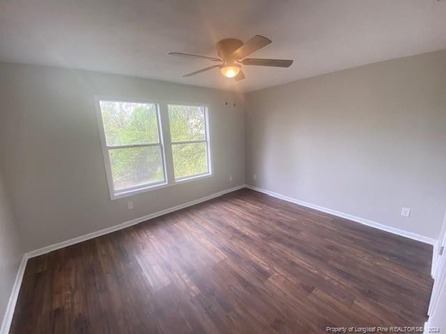 spare room with dark wood-type flooring and ceiling fan