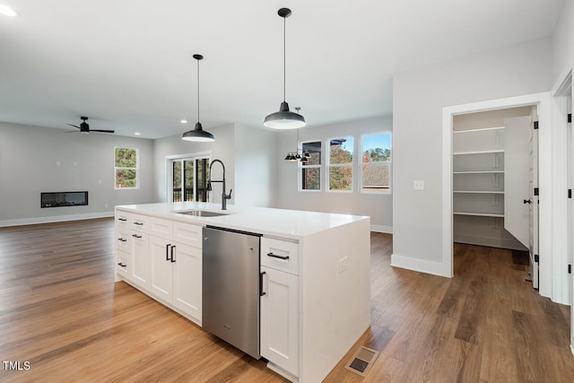 kitchen with light hardwood / wood-style floors, sink, a healthy amount of sunlight, and a kitchen island with sink