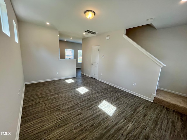 unfurnished living room featuring visible vents, baseboards, dark wood-style floors, and stairway