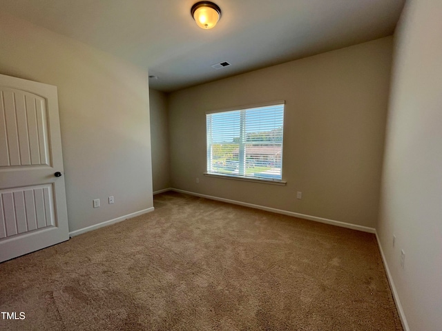 empty room with carpet flooring, visible vents, and baseboards