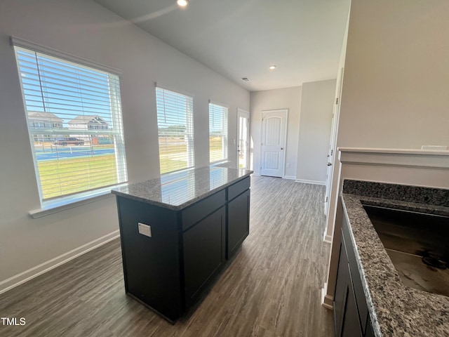 kitchen with sink, dark hardwood / wood-style floors, a center island, and stone counters