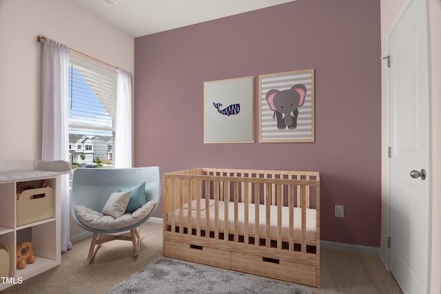 carpeted bedroom featuring a crib and baseboards