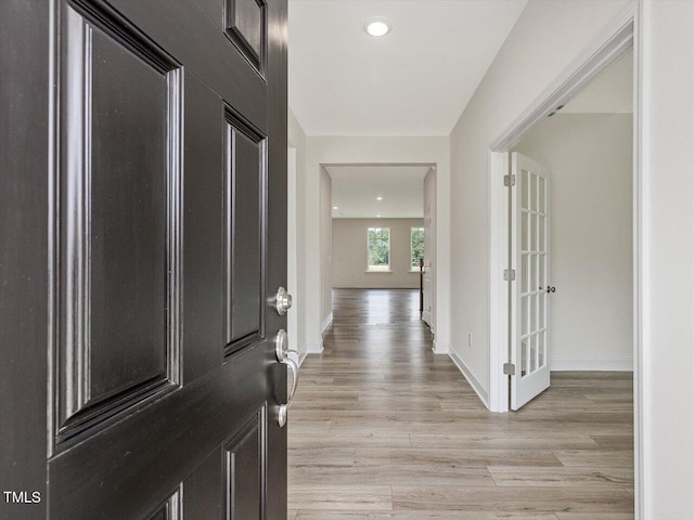 foyer with baseboards and light wood-style floors