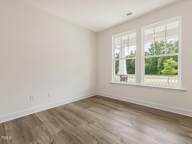 empty room with visible vents, baseboards, and wood finished floors