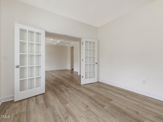 empty room featuring light wood finished floors, french doors, and baseboards