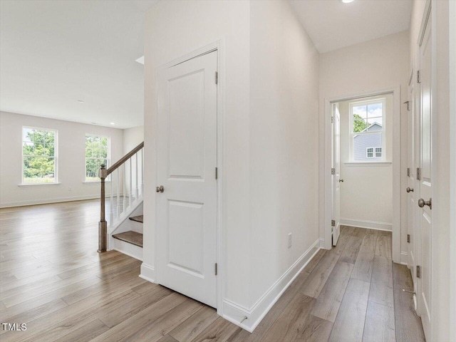 interior space featuring light wood-style floors, baseboards, and stairway