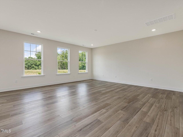 spare room featuring visible vents, baseboards, and wood finished floors