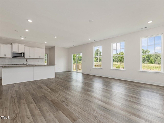 unfurnished living room with baseboards, wood finished floors, visible vents, and recessed lighting